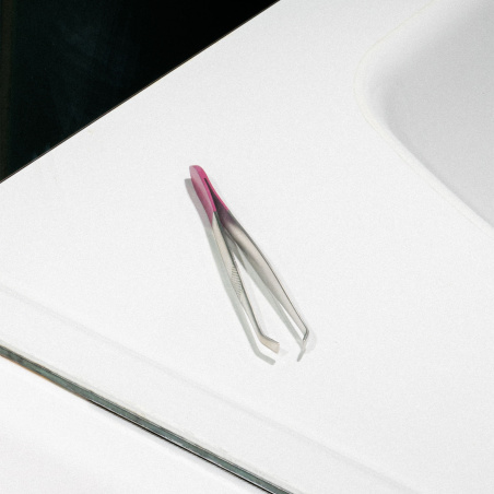 Le reflet de la pince à épiler dans un miroir de la salle de bain.