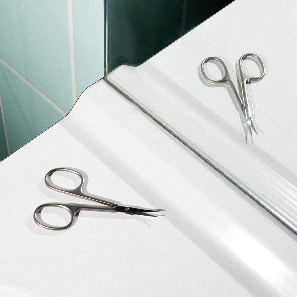 Le ciseaux cuticules sur le bord d'un lavabo dans une salle de bain.