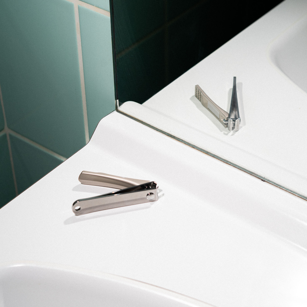 Le coupe ongle premium sur le rebord d'un lavabo avec sa lime intégrée.