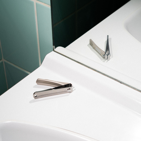 Le coupe ongle premium sur le rebord d'un lavabo avec sa lime intégrée.
