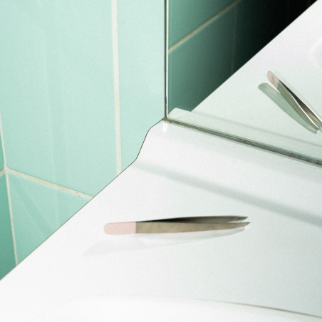 La pince à épiler professionnelle avec mors bais sur le bord d'un lavabo.